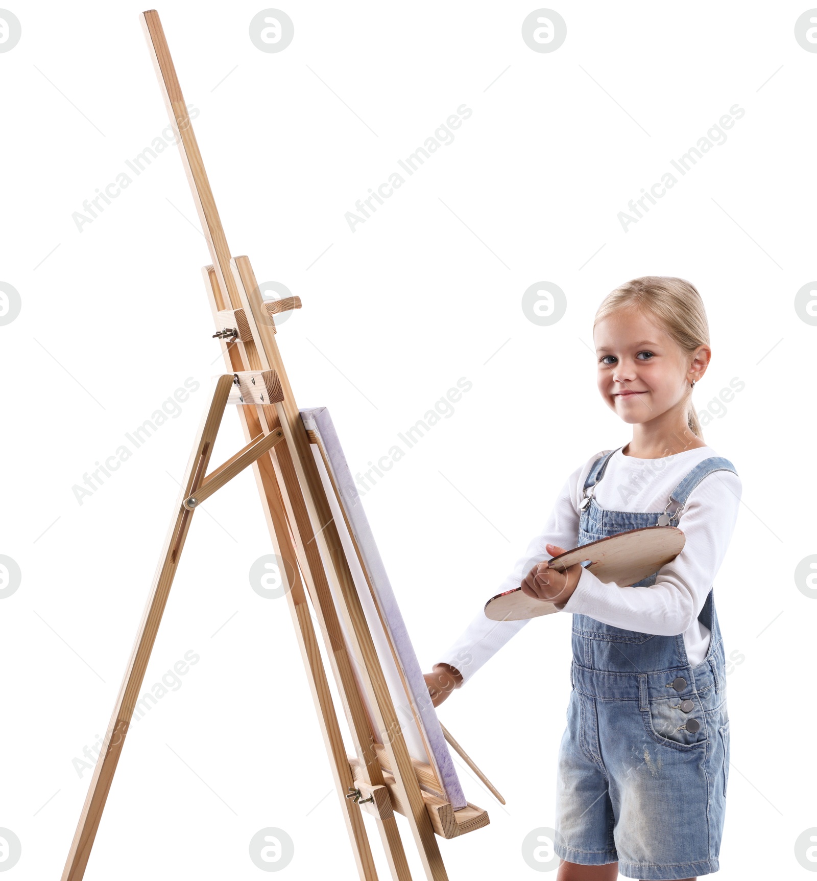 Photo of Choice of profession. Little girl with palette of paints and brush near easel pretending to be artist on white background