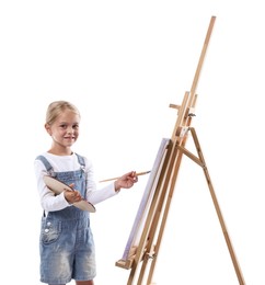Photo of Choice of profession. Little girl with palette of paints and brush near easel pretending to be artist on white background