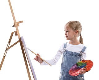 Photo of Choice of profession. Little girl with palette of paints and brush near easel pretending to be artist on white background