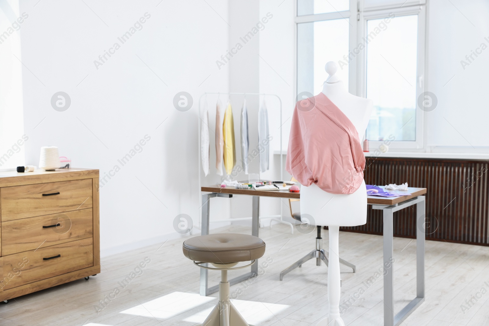 Photo of Female mannequin with fabric and sewing supplies in atelier