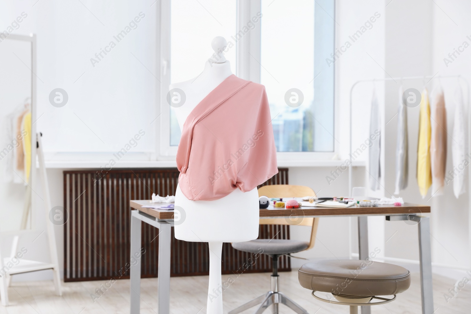 Photo of Female mannequin with fabric and sewing supplies in atelier