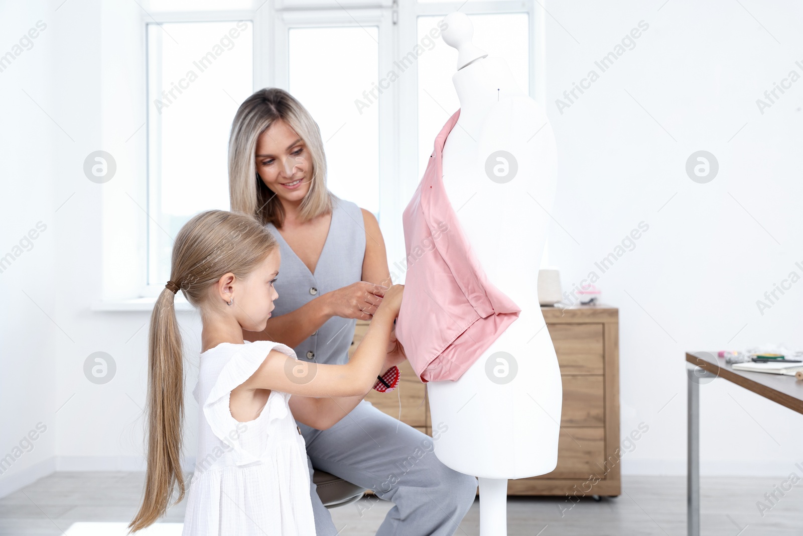 Choice of profession. Little girl helping her mother working with mannequin in atelier Photo of Choice of profession. Little girl helping her mother working with mannequin in atelier