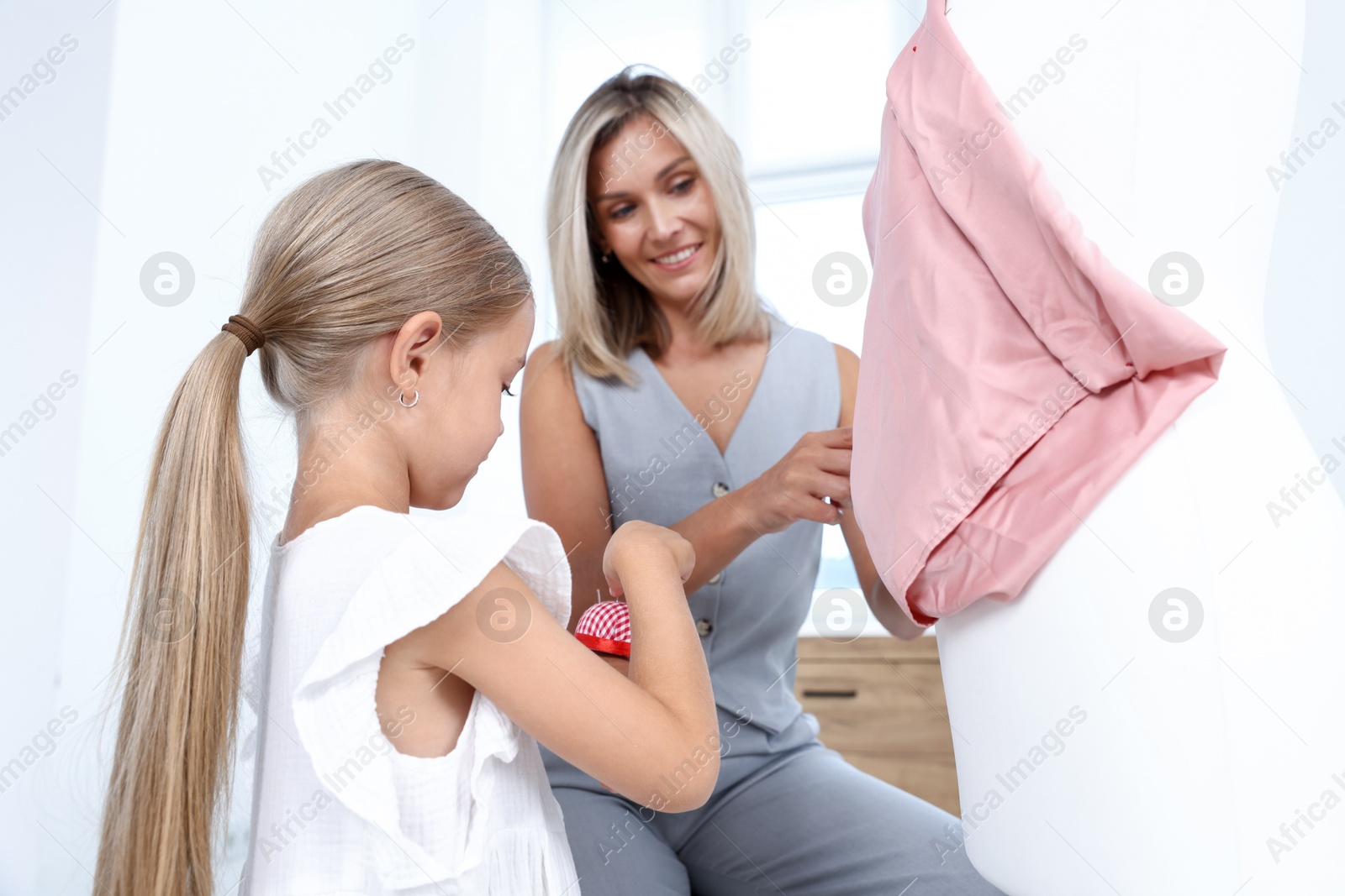 Choice of profession. Little girl helping her mother working with mannequin in atelier, low angle view Photo of Choice of profession. Little girl helping her mother working with mannequin in atelier, low angle view