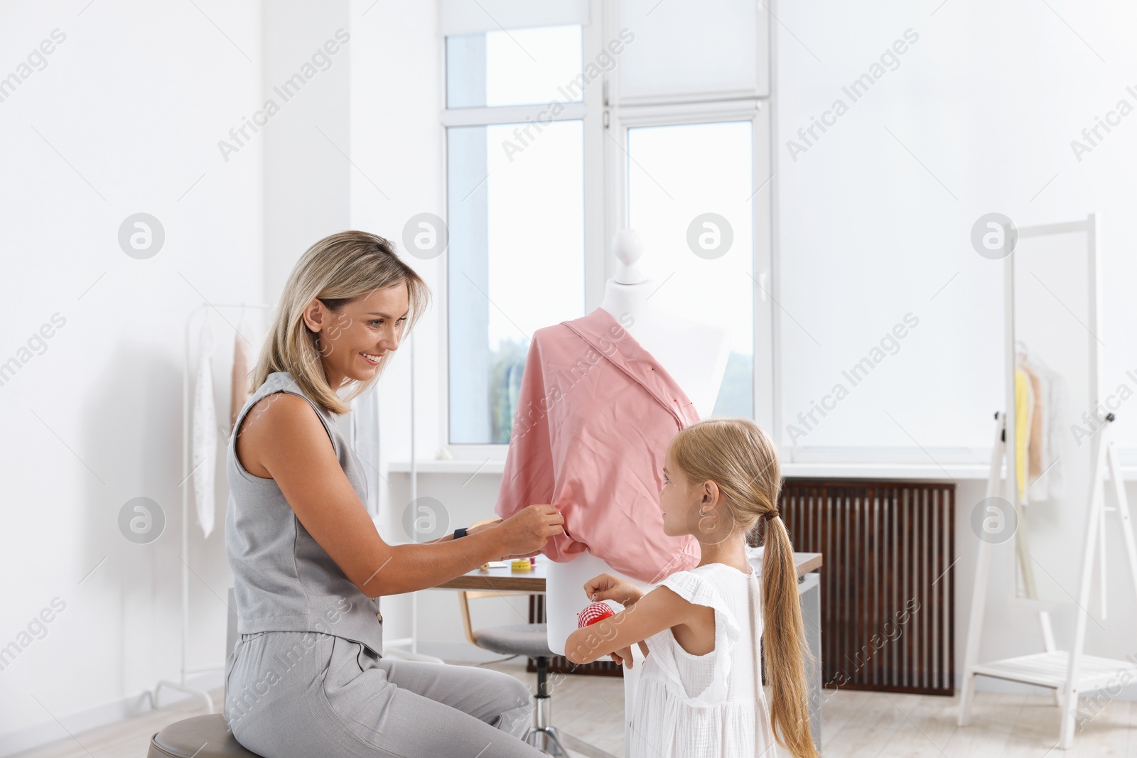Choice of profession. Little girl helping her mother working with mannequin in atelier Photo of Choice of profession. Little girl helping her mother working with mannequin in atelier