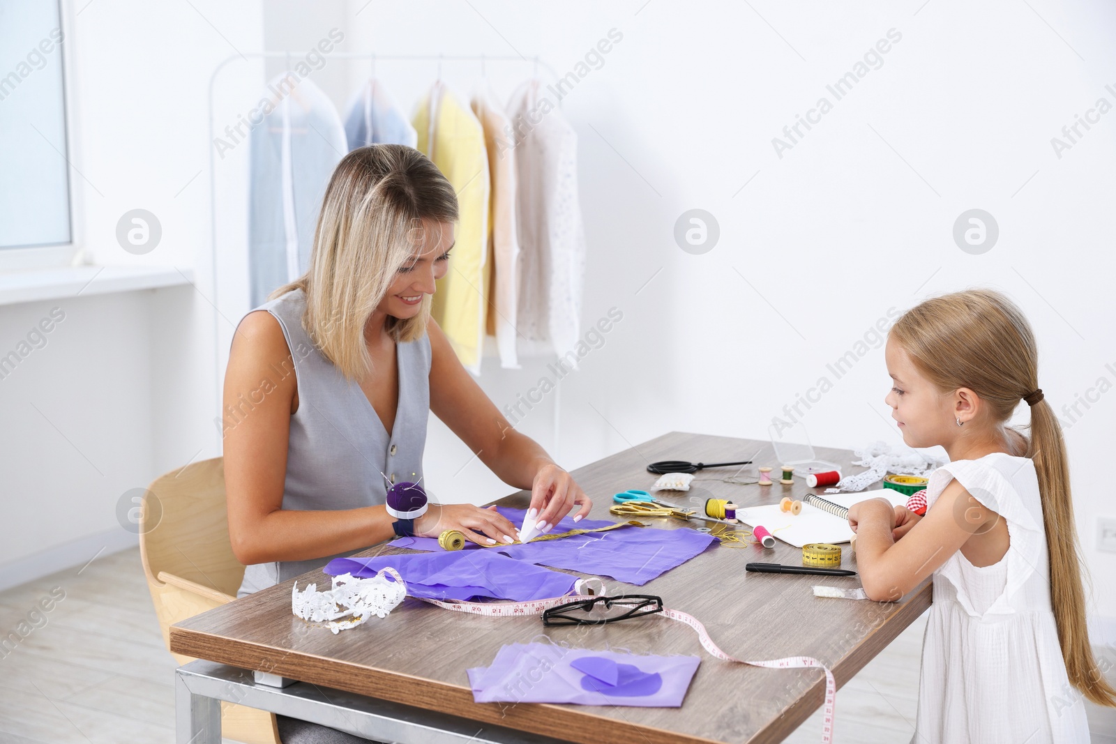 Photo of Choice of profession. Little girl helping her mother working in atelier