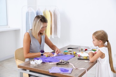 Photo of Choice of profession. Little girl helping her mother working in atelier