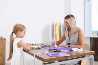 Photo of Choice of profession. Little girl helping her mother working in atelier