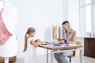 Photo of Choice of profession. Little girl helping her mother working in atelier