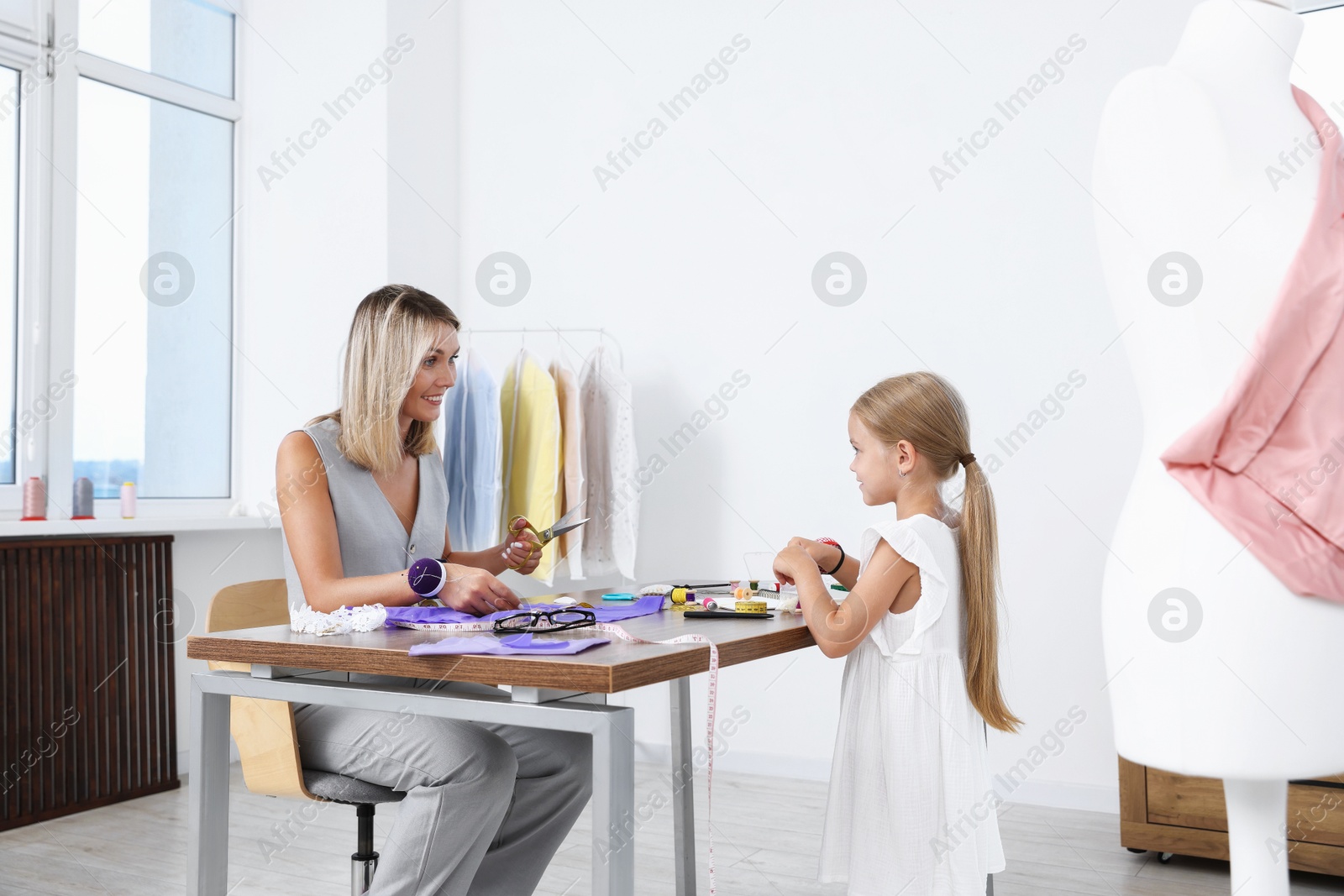 Photo of Choice of profession. Little girl helping her mother working in atelier