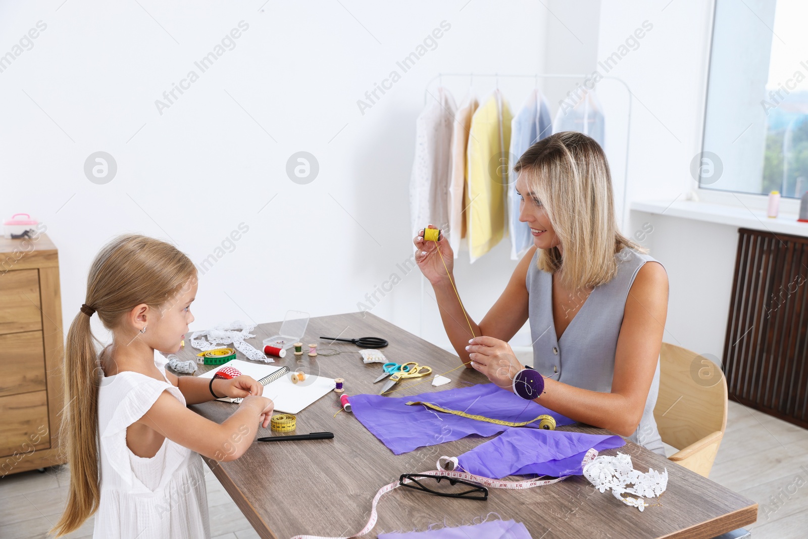 Photo of Choice of profession. Little girl helping her mother working in atelier