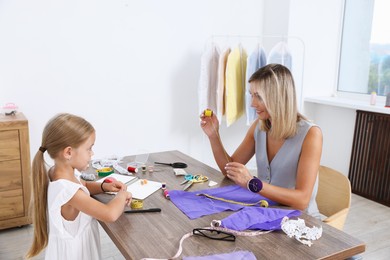 Photo of Choice of profession. Little girl helping her mother working in atelier