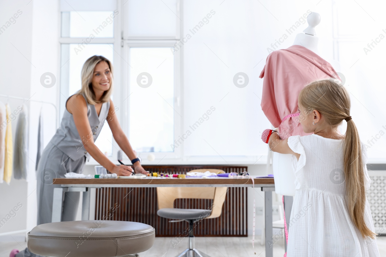 Photo of Choice of profession. Little girl helping her mother working in atelier, selective focus