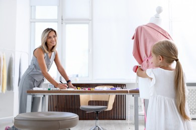 Photo of Choice of profession. Little girl helping her mother working in atelier, selective focus