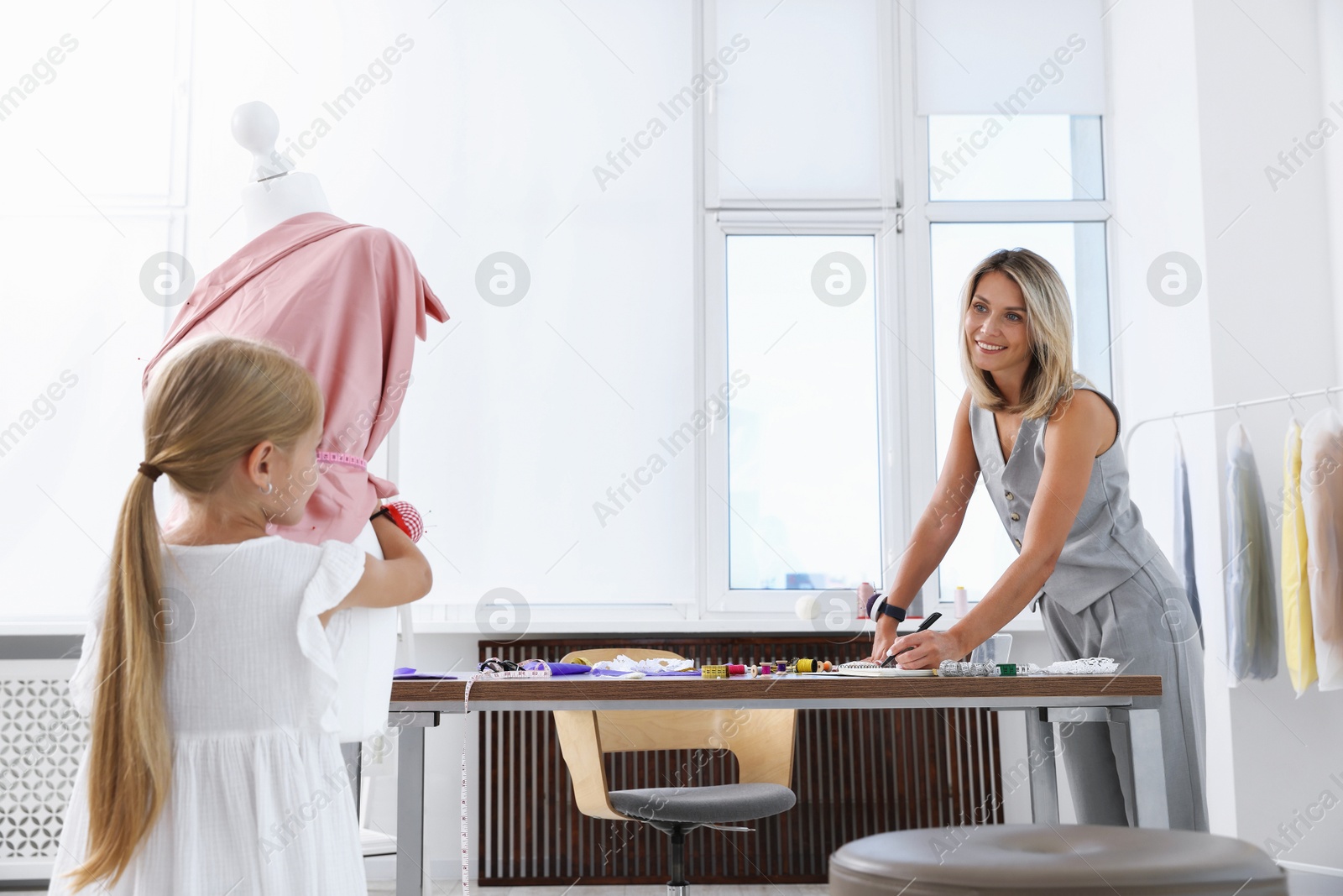 Photo of Choice of profession. Little girl helping her mother working in atelier