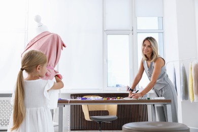 Photo of Choice of profession. Little girl helping her mother working in atelier