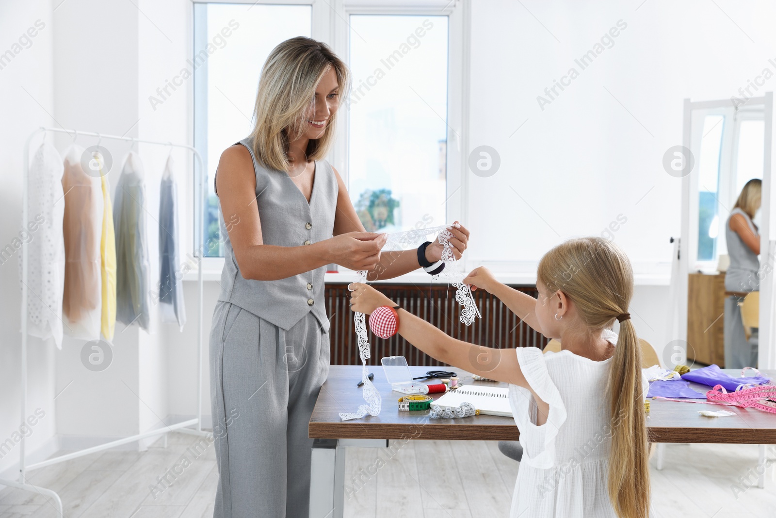Photo of Choice of profession. Little girl helping her mother working in atelier