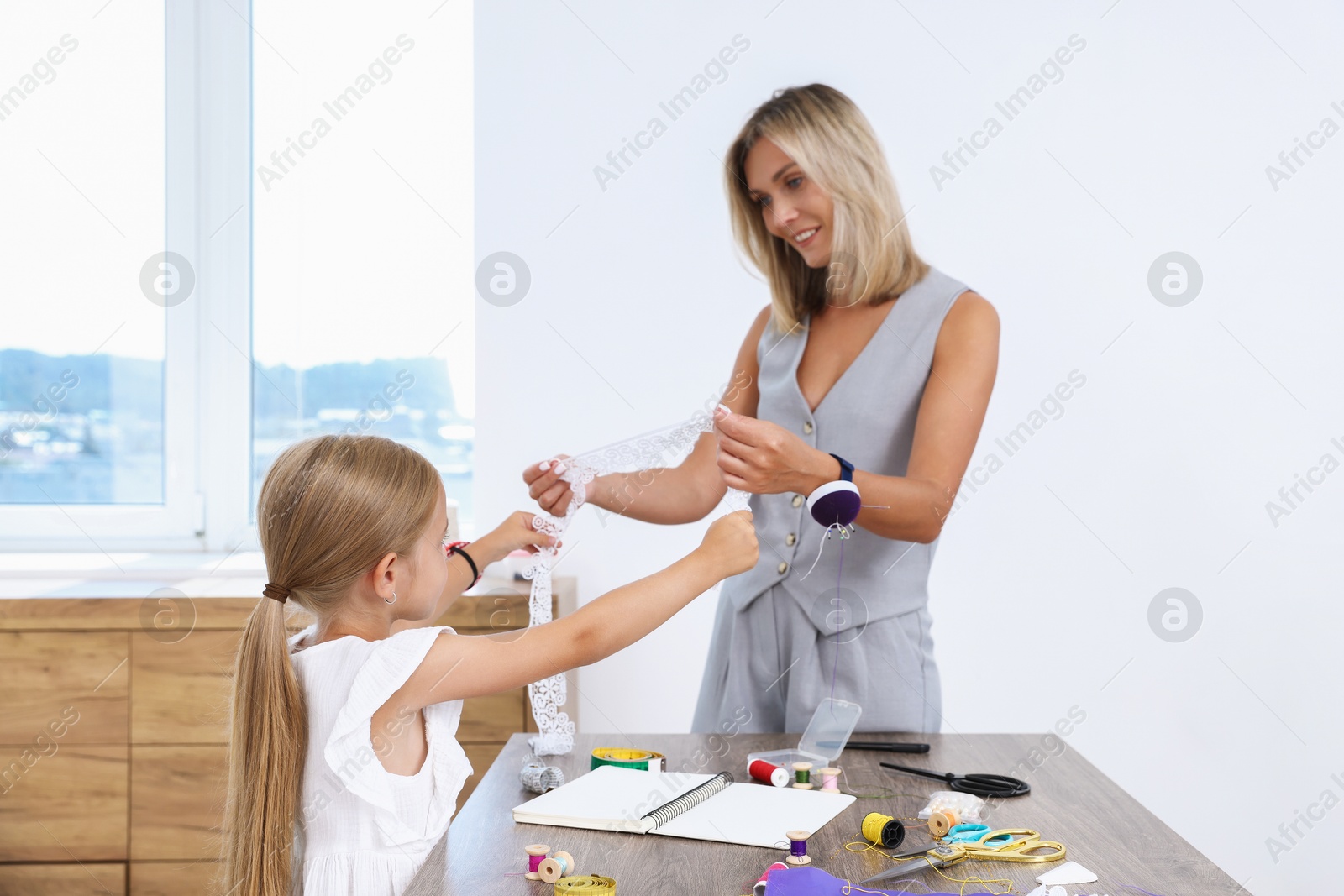 Photo of Choice of profession. Little girl helping her mother working in atelier