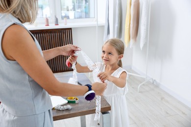 Photo of Choice of profession. Little girl helping her mother working in atelier
