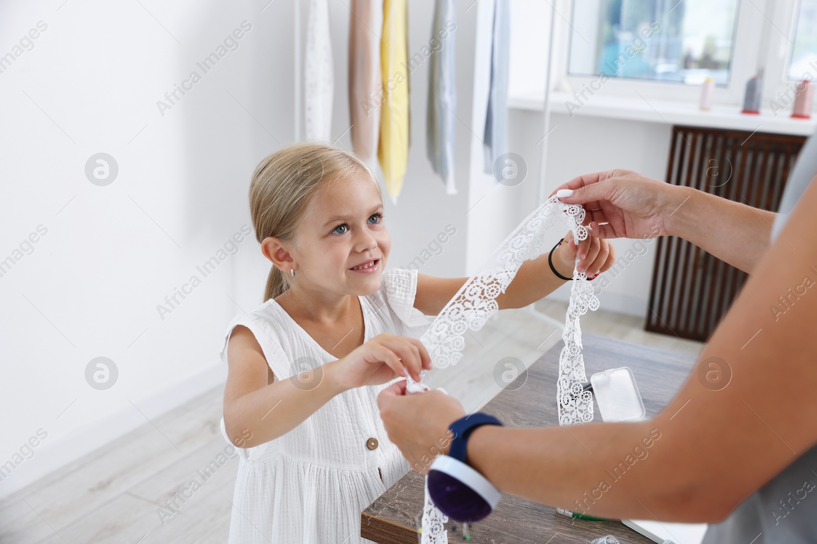 Photo of Choice of profession. Little girl helping her mother working in atelier