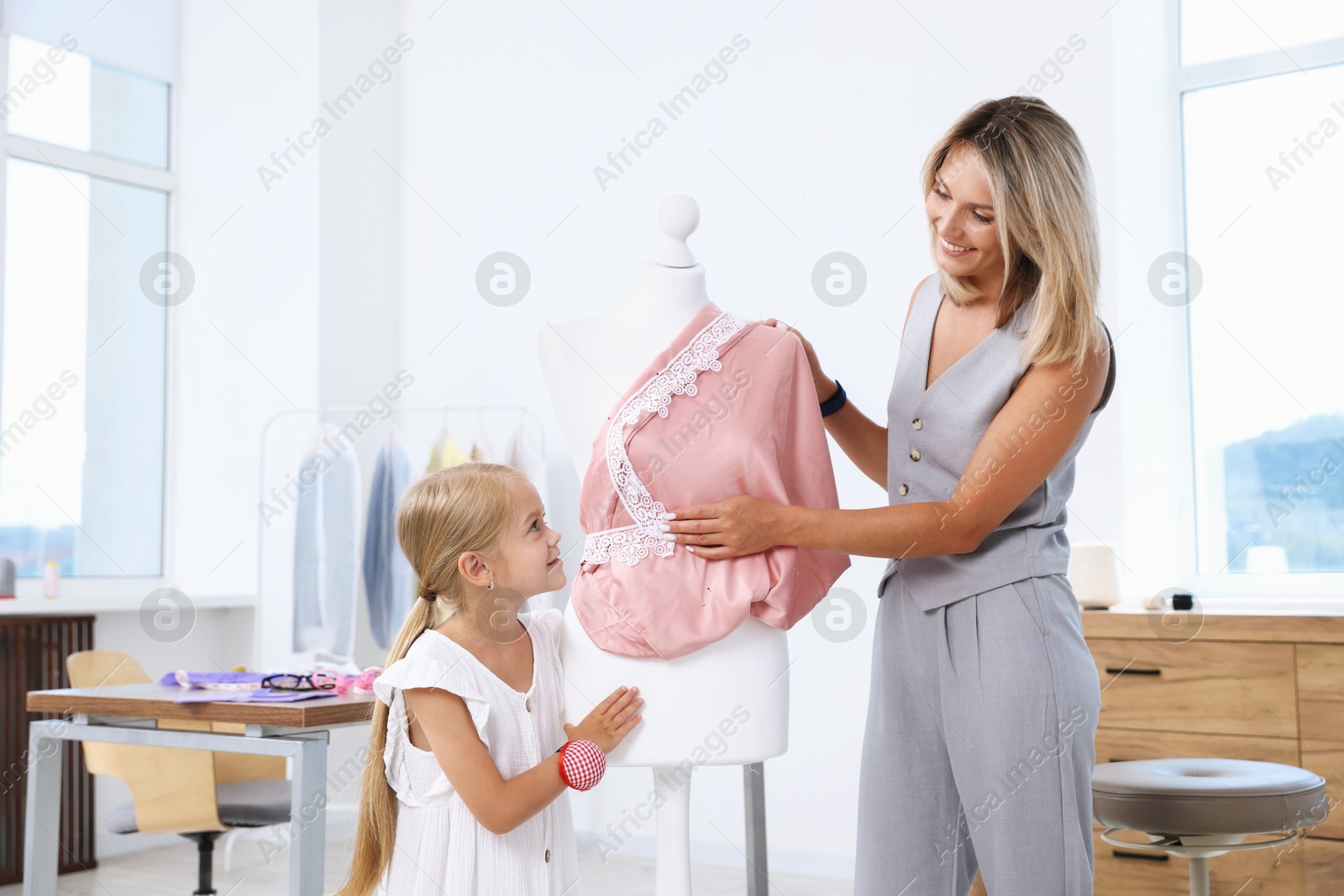 Photo of Choice of profession. Little girl helping her mother working with mannequin in atelier