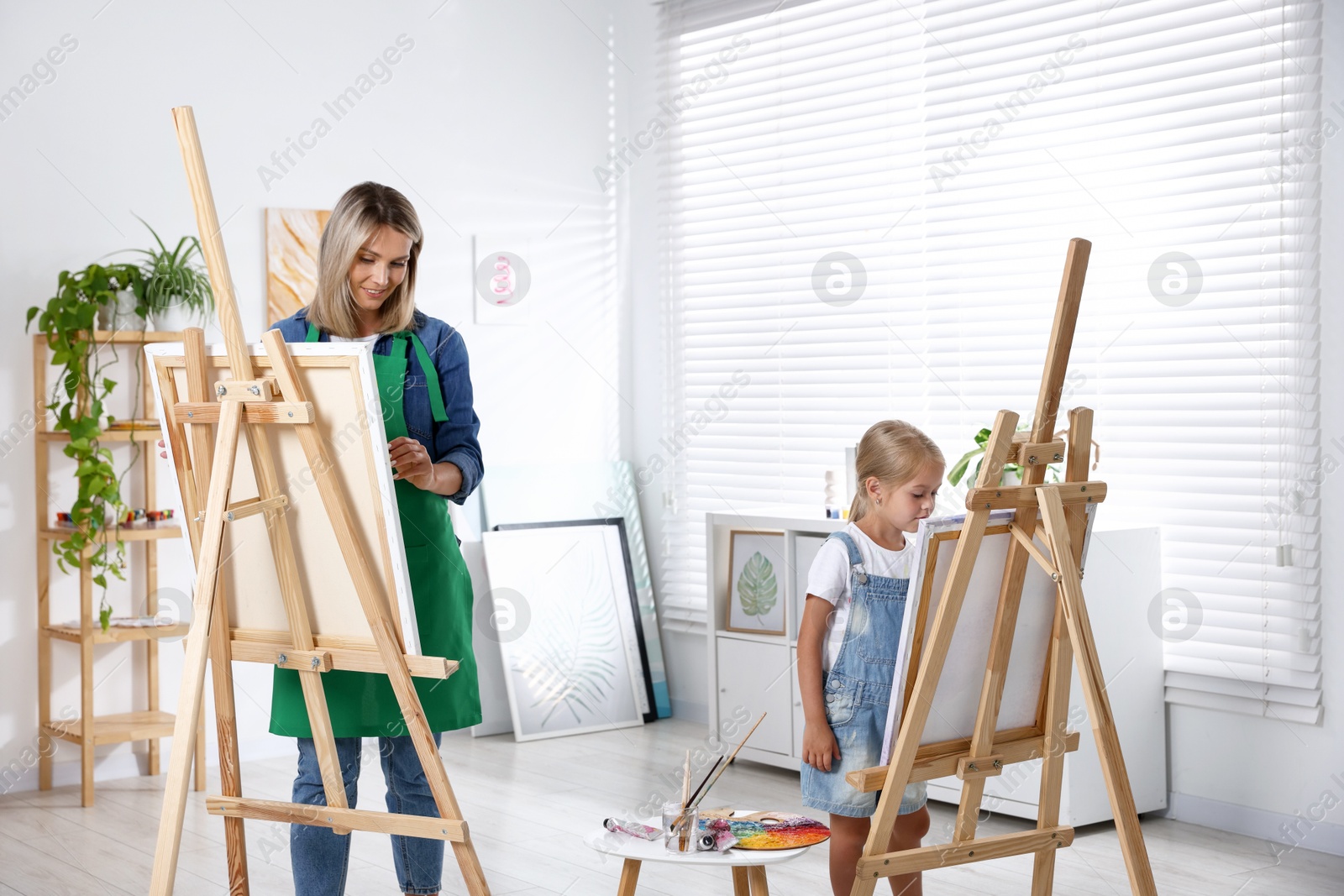 Photo of Choice of profession. Mother teaching her daughter to paint in studio