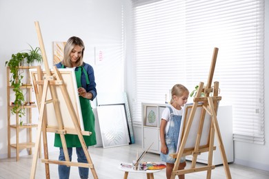 Photo of Choice of profession. Mother teaching her daughter to paint in studio