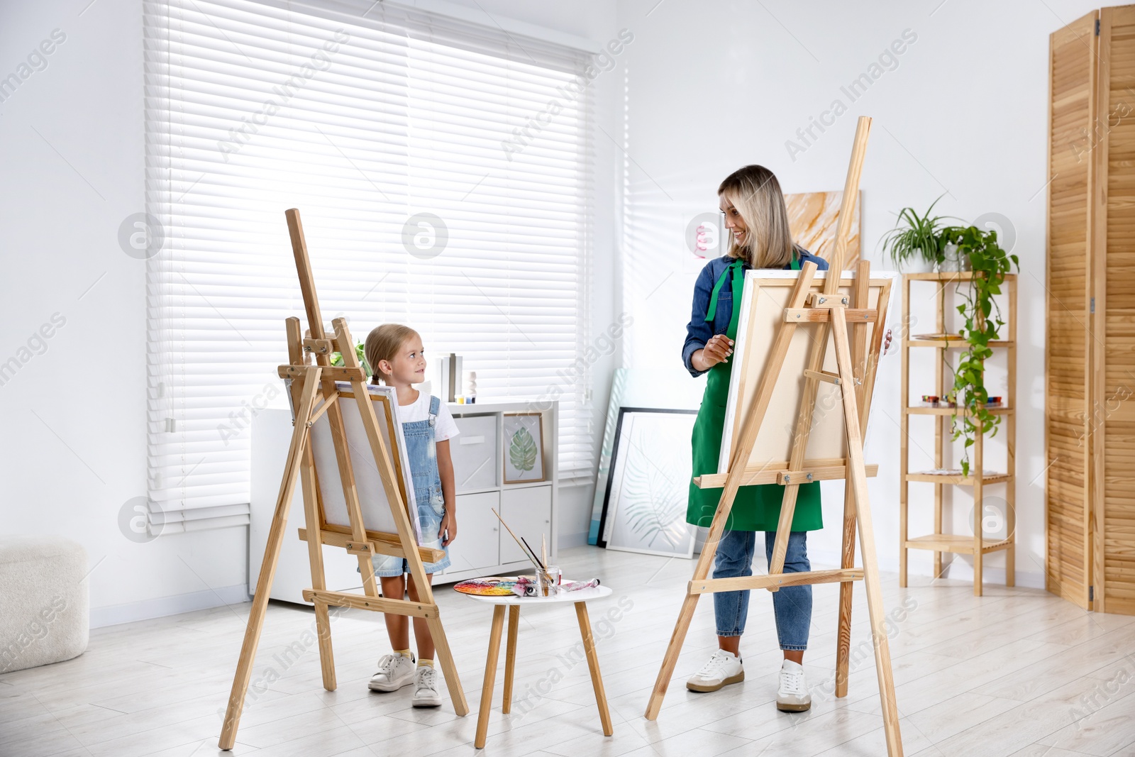 Photo of Choice of profession. Mother teaching her daughter to paint in studio
