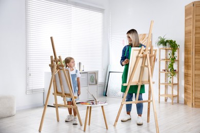 Photo of Choice of profession. Mother teaching her daughter to paint in studio