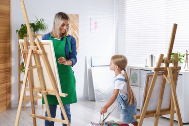 Photo of Choice of profession. Mother teaching her daughter to paint in studio