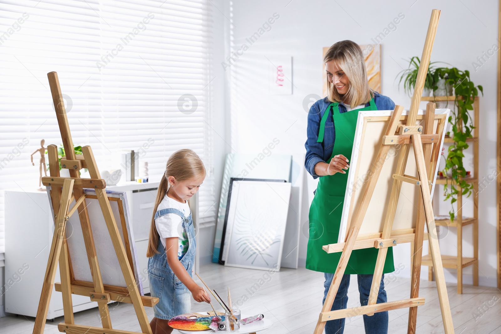 Photo of Choice of profession. Mother teaching her daughter to paint in studio