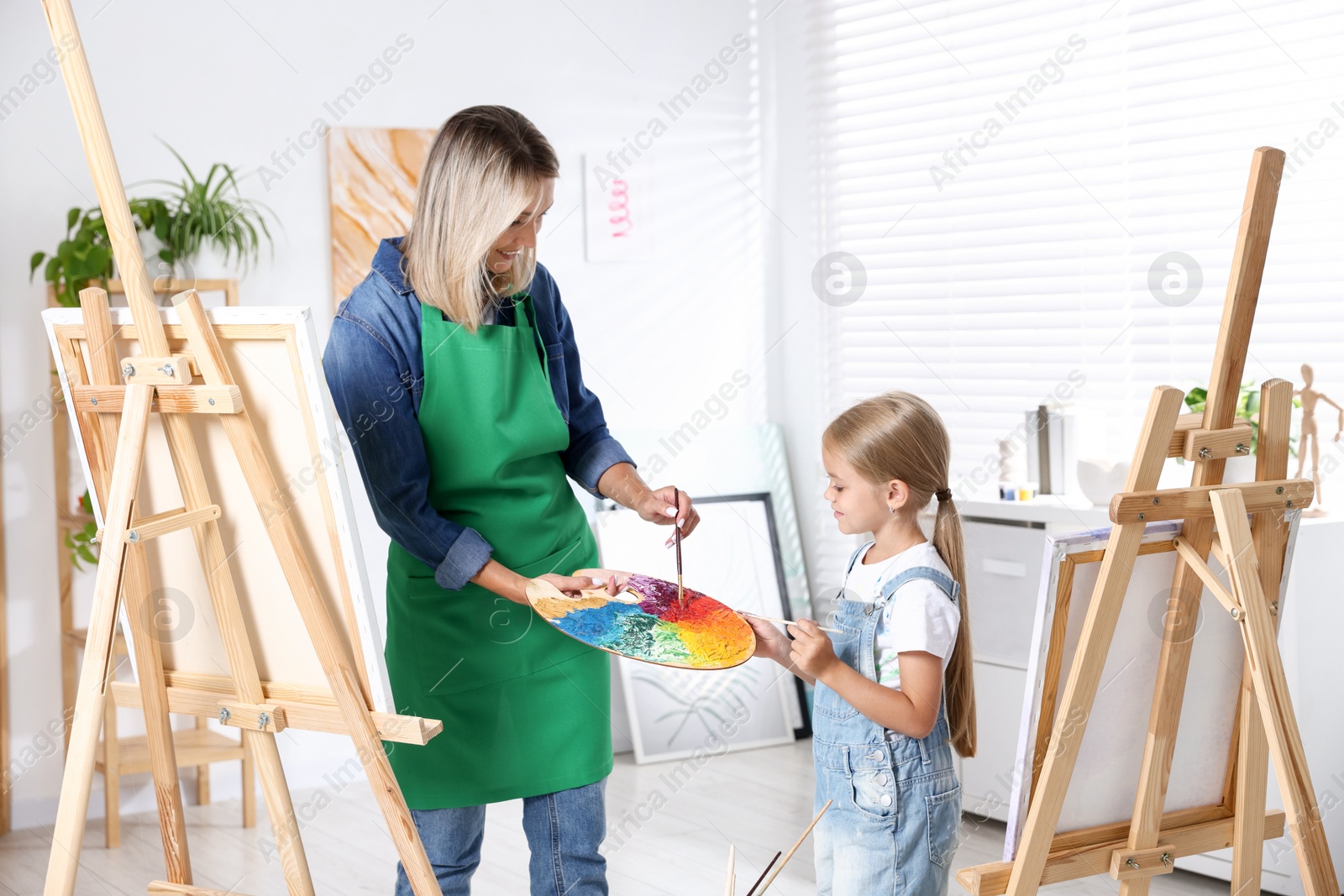 Photo of Choice of profession. Mother teaching her daughter to paint in studio