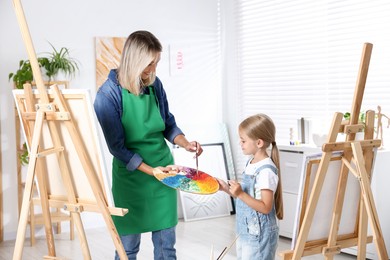 Photo of Choice of profession. Mother teaching her daughter to paint in studio