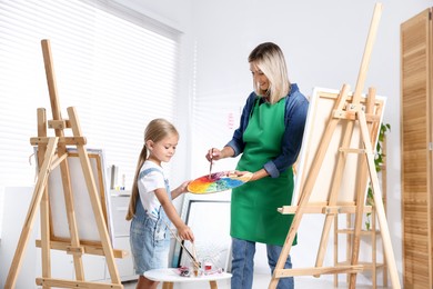 Photo of Choice of profession. Mother teaching her daughter to paint in studio