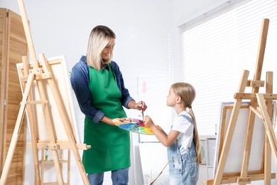 Photo of Choice of profession. Mother teaching her daughter to paint in studio