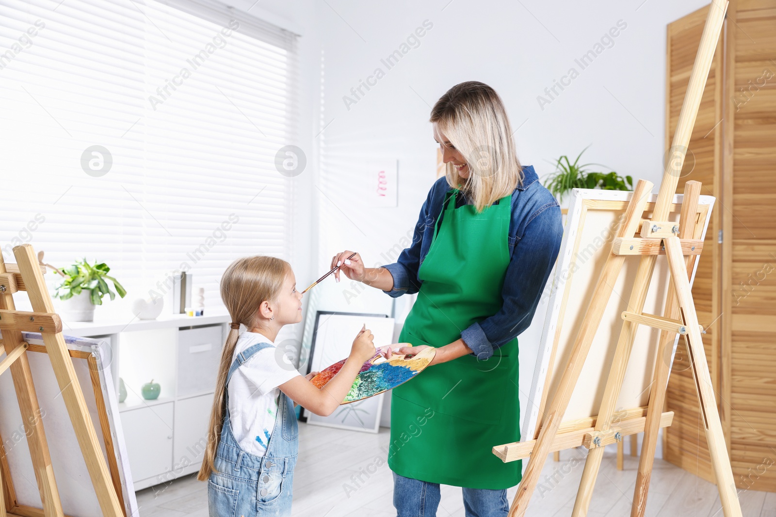 Photo of Choice of profession. Mother teaching her daughter to paint in studio