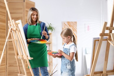 Photo of Choice of profession. Mother teaching her daughter to paint in studio