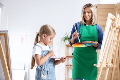 Photo of Choice of profession. Mother teaching her daughter to paint in studio