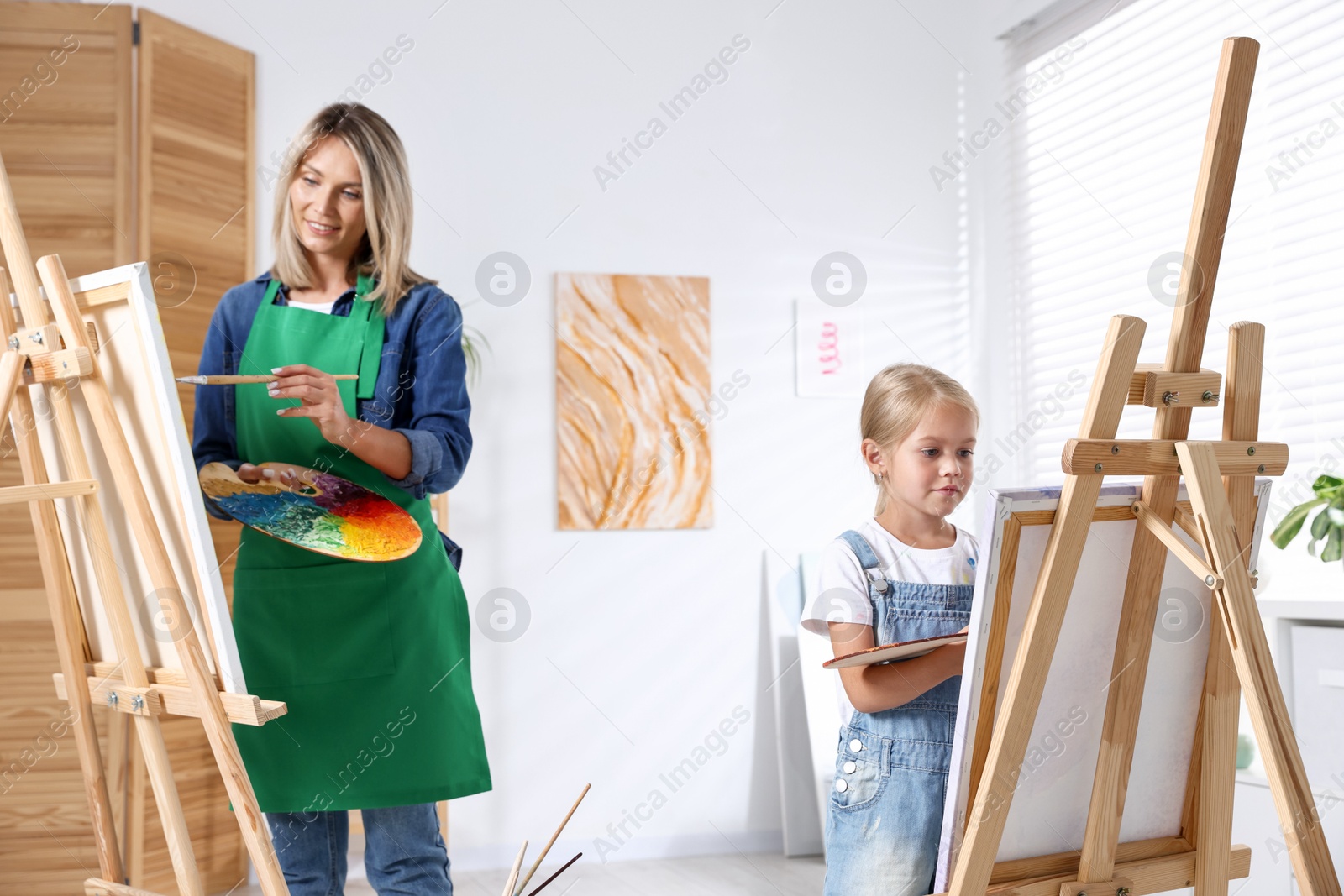 Photo of Choice of profession. Mother teaching her daughter to paint in studio