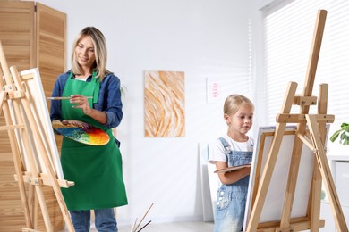 Photo of Choice of profession. Mother teaching her daughter to paint in studio