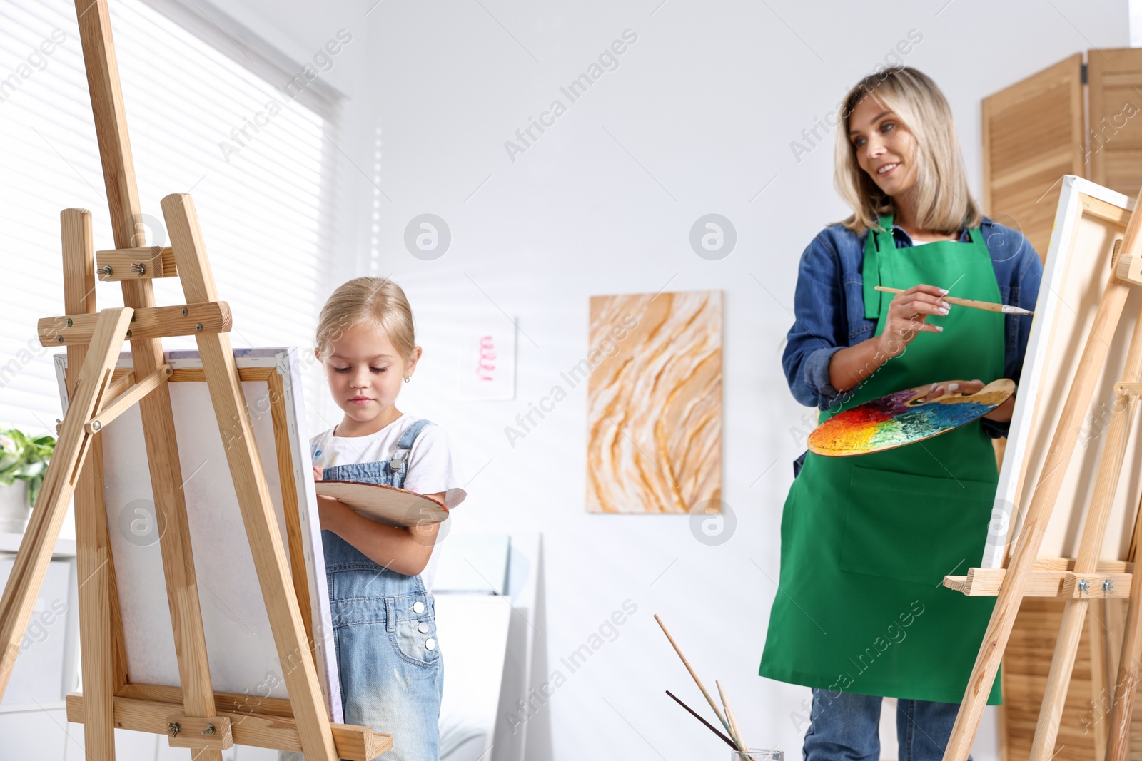 Photo of Choice of profession. Mother teaching her daughter to paint in studio