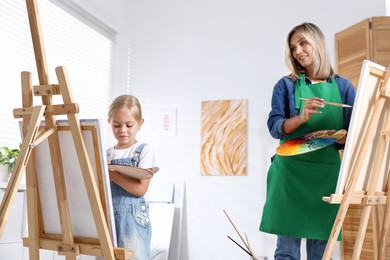 Photo of Choice of profession. Mother teaching her daughter to paint in studio