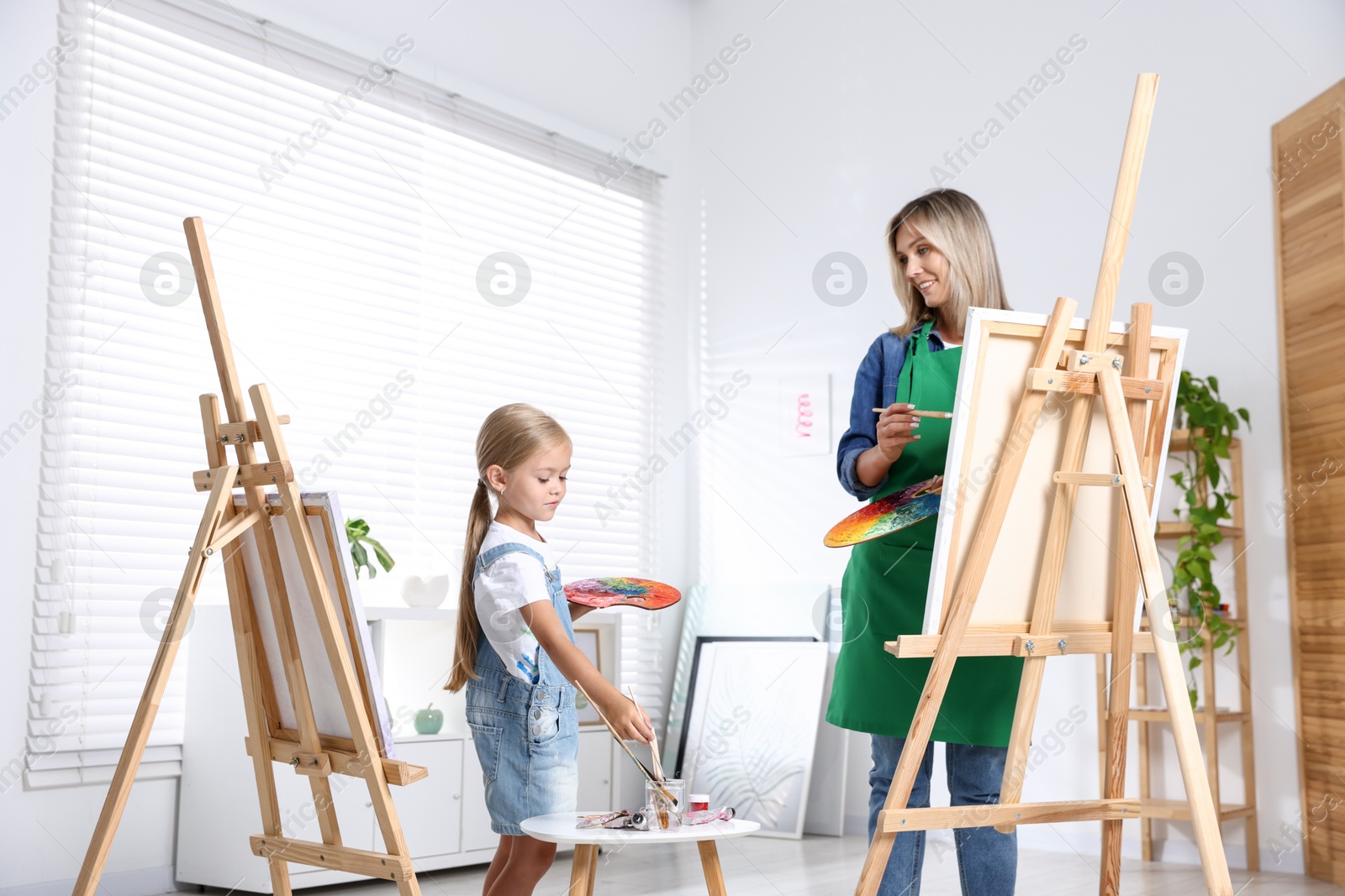 Photo of Choice of profession. Mother teaching her daughter to paint in studio