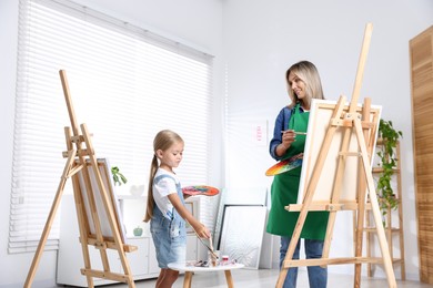 Photo of Choice of profession. Mother teaching her daughter to paint in studio