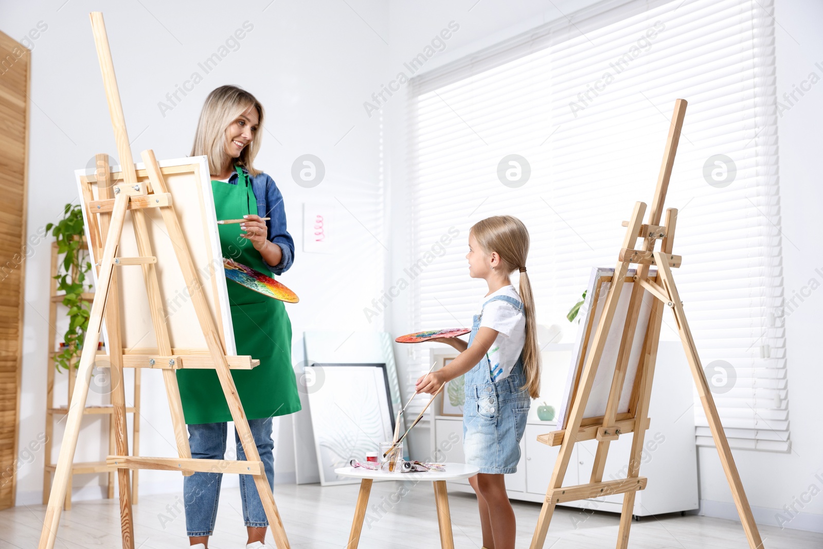 Photo of Choice of profession. Mother teaching her daughter to paint in studio