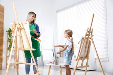 Photo of Choice of profession. Mother teaching her daughter to paint in studio