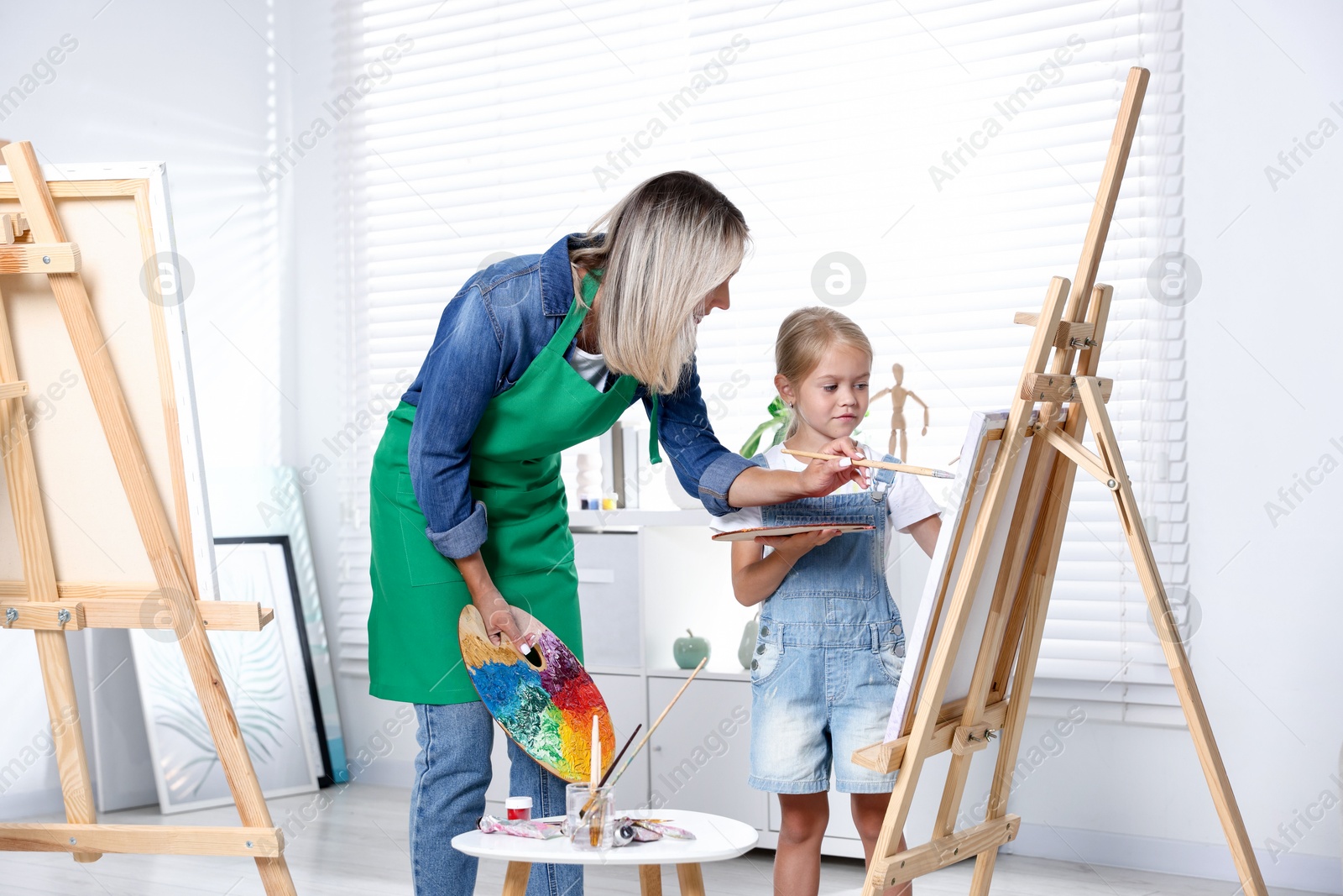 Photo of Choice of profession. Mother teaching her daughter to paint in studio