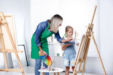 Photo of Choice of profession. Mother teaching her daughter to paint in studio