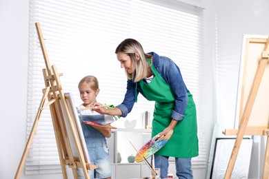 Photo of Choice of profession. Mother teaching her daughter to paint in studio