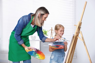 Photo of Choice of profession. Mother teaching her daughter to paint in studio