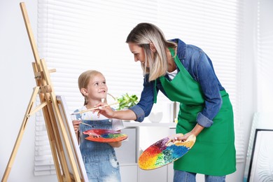 Photo of Choice of profession. Mother teaching her daughter to paint in studio